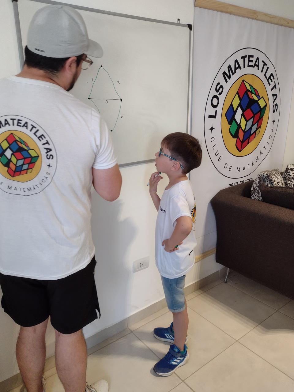 Profesor explicando geometría en el pizarrón con alumno